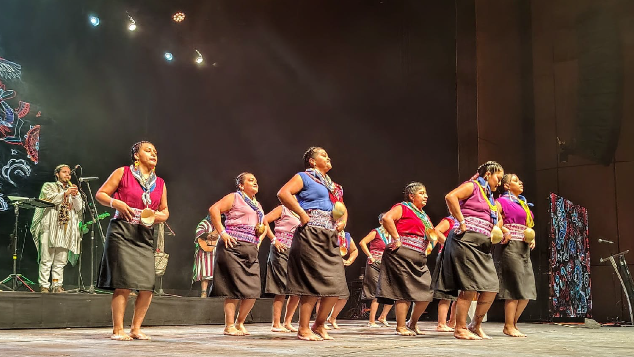 Grupo de mujeres indígenas interpretando una danza tradicional en tarima, durante el Encuentro Distrital de Pueblos Indígenas 2025 en Bogotá.