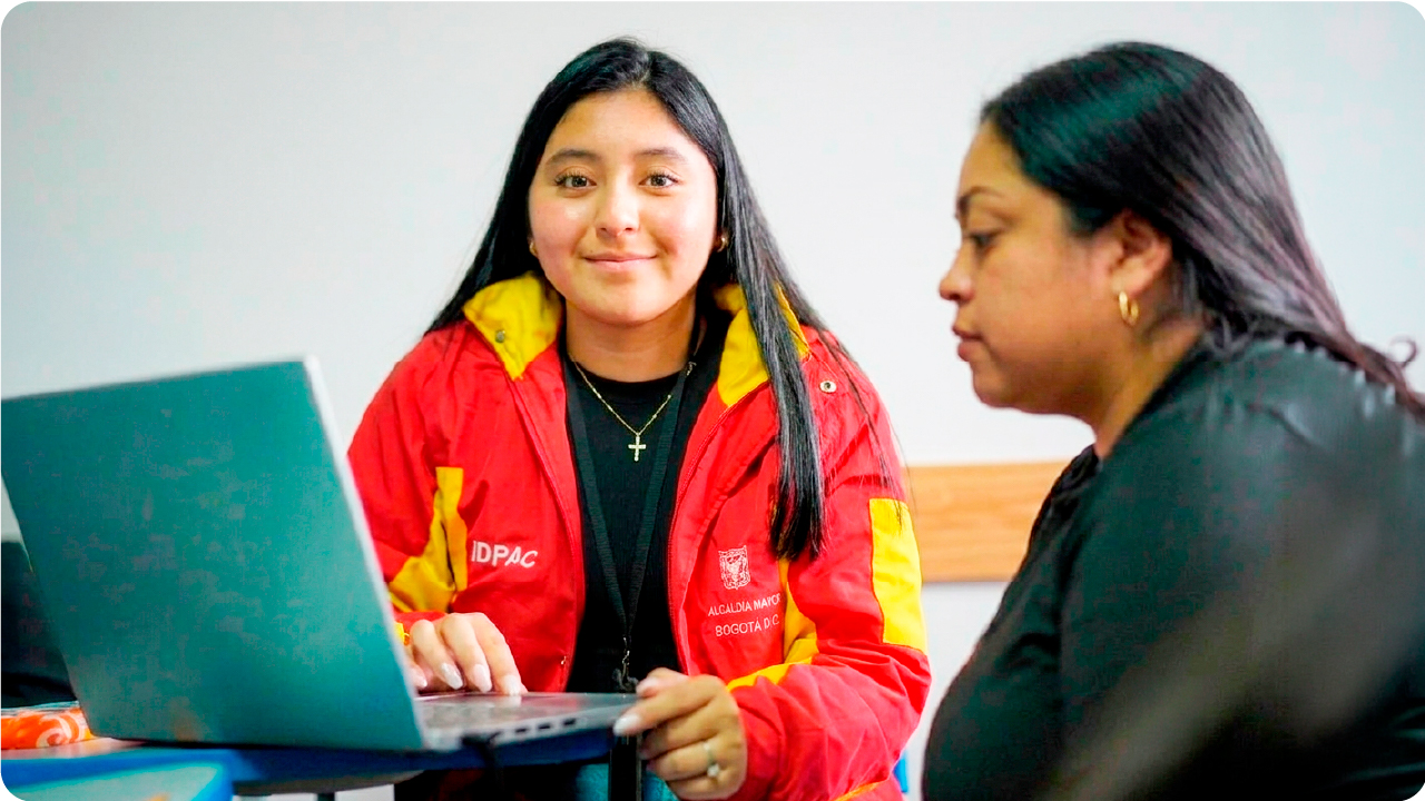 Persona funcionaria del IDPAC brinda orientación a un ciudadano durante una atención presencial con apoyo de un computador portátil, en el marco de las acciones del Defensor de la Ciudadanía.