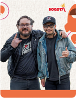 Dos jóvenes abrazados, vistiendo chaquetas y haciendo señas con las manos, sobre un fondo claro con el logotipo de Bogotá y elementos gráficos juveniles como un cohete naranja.