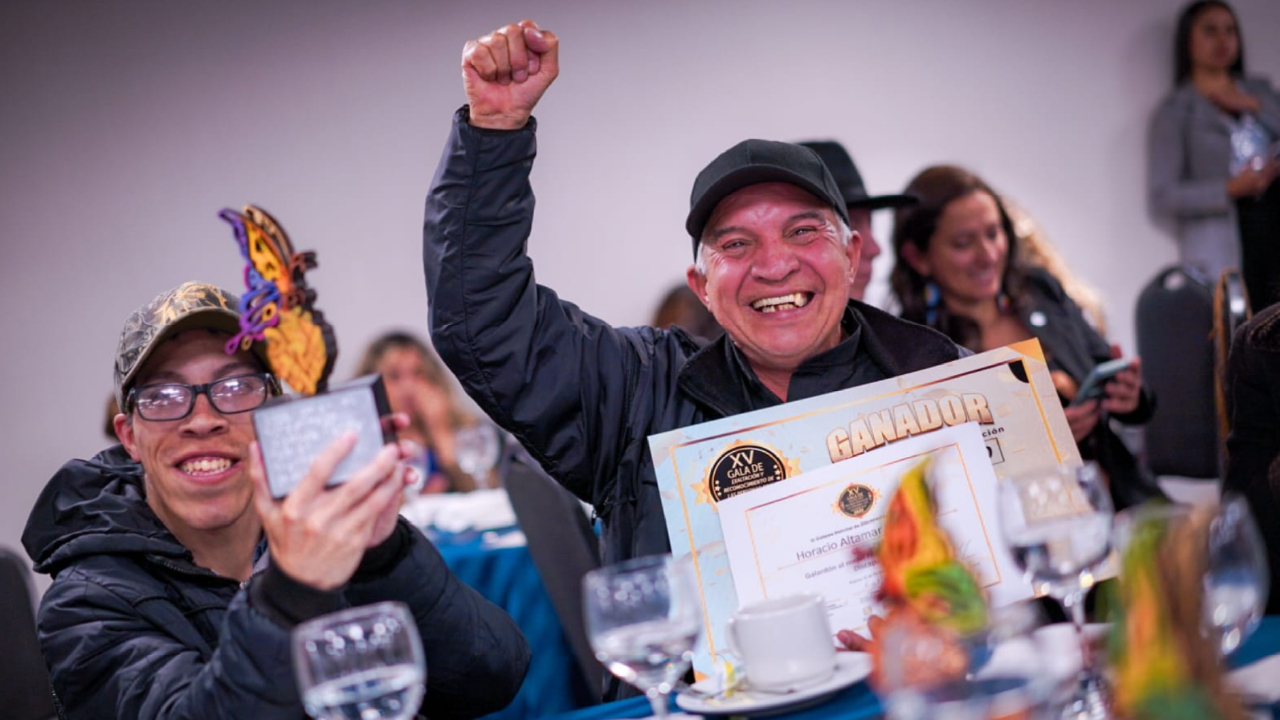 Ganadores celebrando en la XV Gala de Reconocimiento a la Participación, mostrando con orgullo sus trofeos y diplomas por su labor destacada en Bogotá