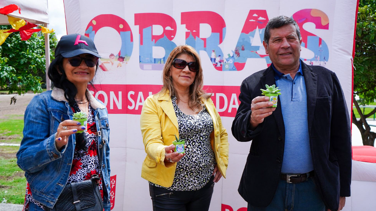 Personas de la comunidad participan en la entrega simbólica de plantas durante una jornada de obras comunitarias en Bogotá.