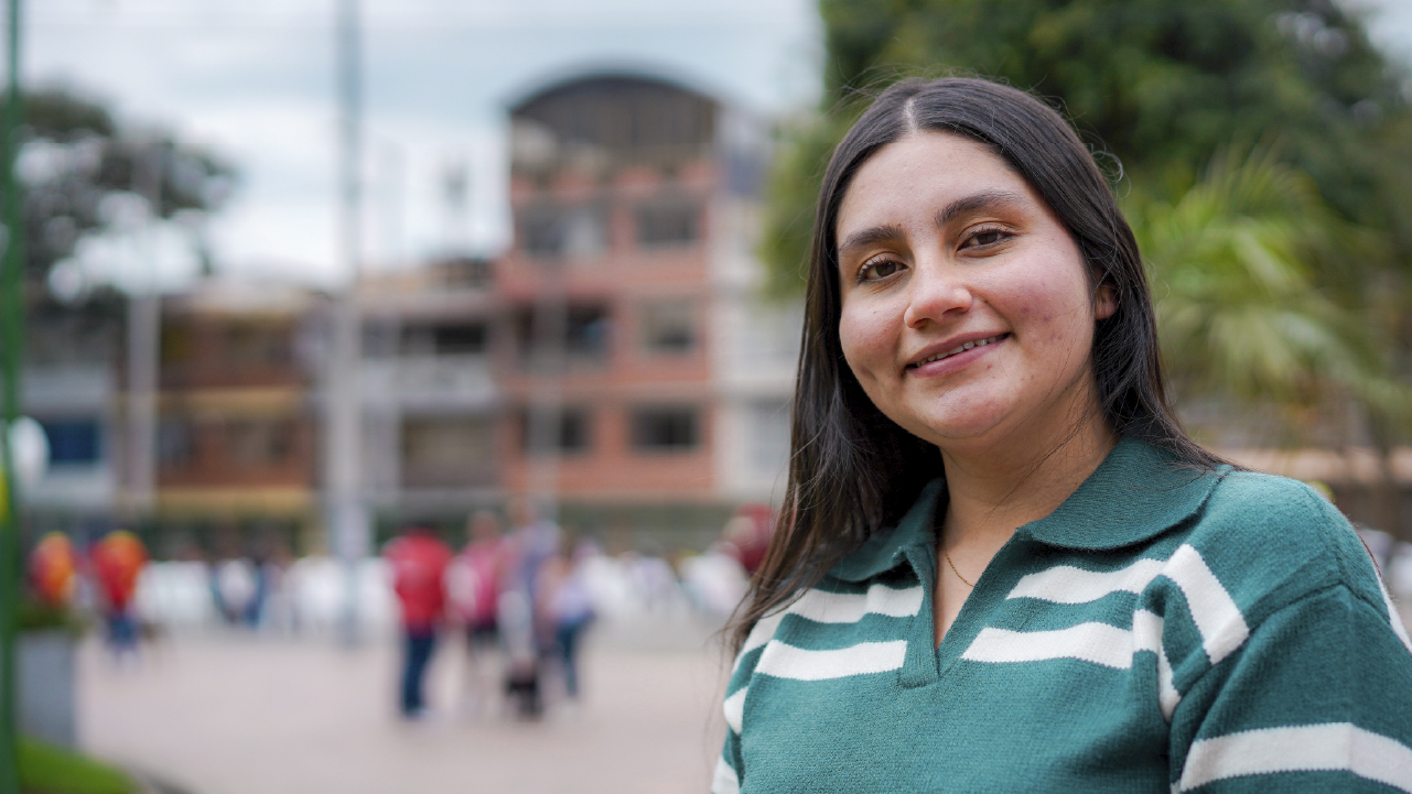 Mujer joven sonriente, potencial votante, en un espacio comunitario de Bogotá, representando la participación ciudadana en la cuenta regresiva para las elecciones comunales.