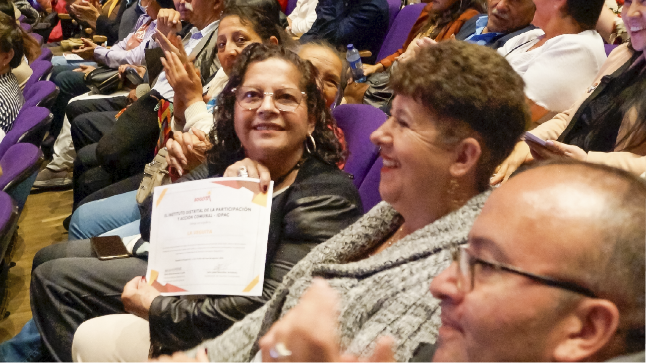 Ciudadana muestra su certificado de posesión como líder comunal del IDPAC, durante el acto de posesión de 1.600 líderes y lideresas de acción comunal en Bogotá.