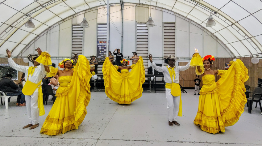 Grupo de bailarines afrodescendientes en trajes típicos amarillos interpretando danza tradicional del Pacífico colombiano durante un evento cultural en Bogotá